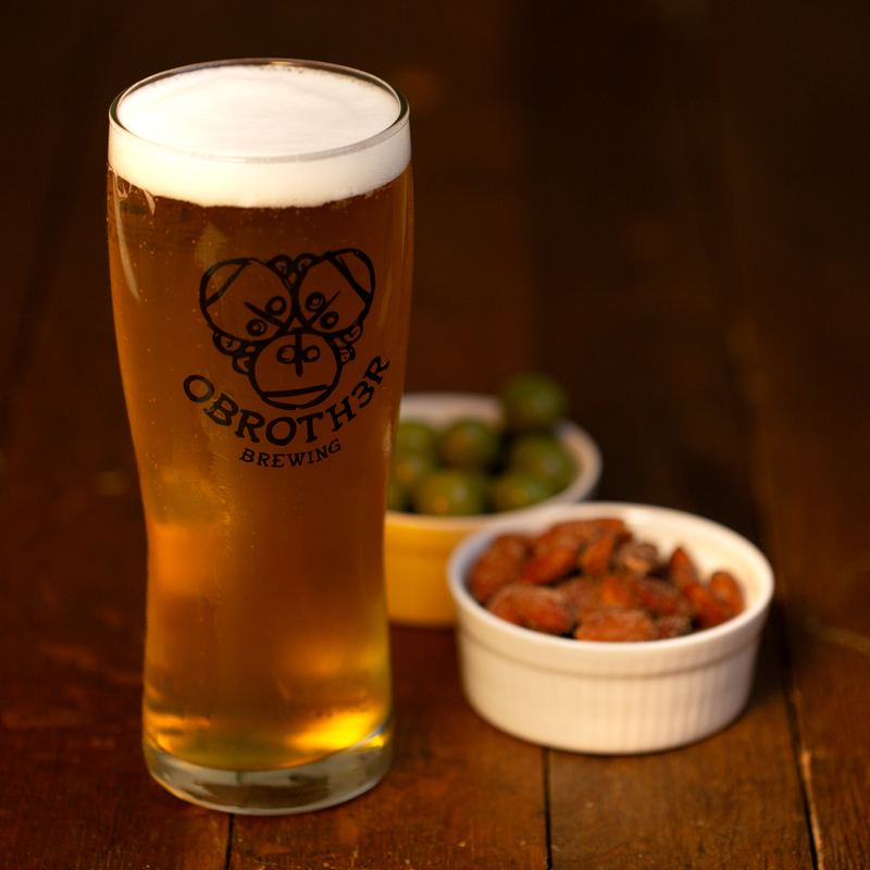 A glass of craft beer with olives and smoked almonds