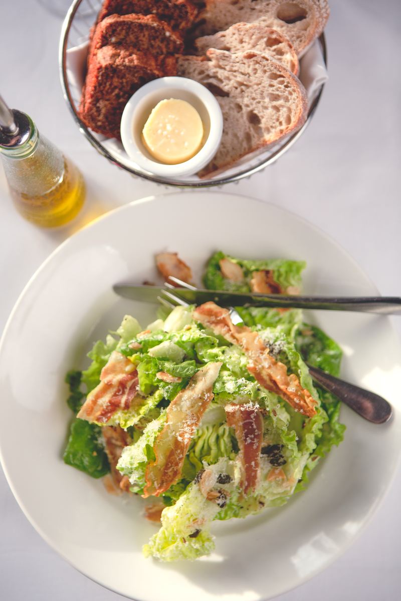 Caesar salad with bread and olive oil on a white tablecloth
