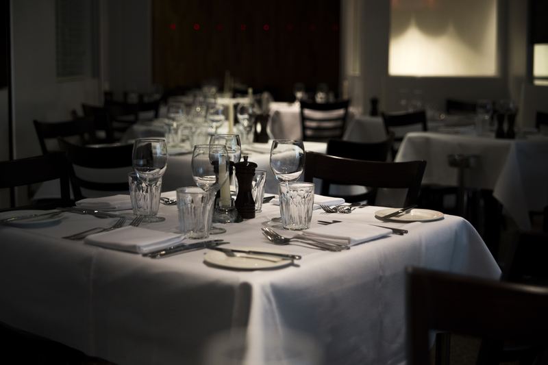 The dining room set for service with white linen tablecloths