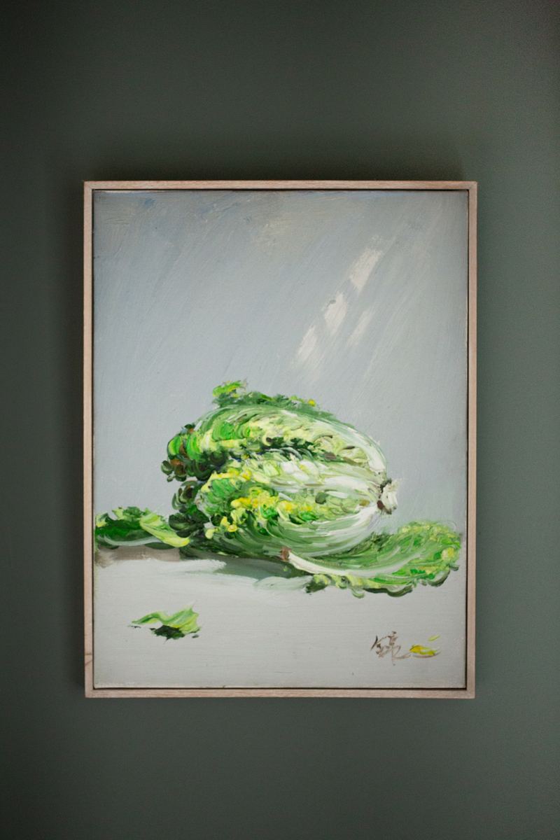 Painting of a head of lettuce on a dark green wall