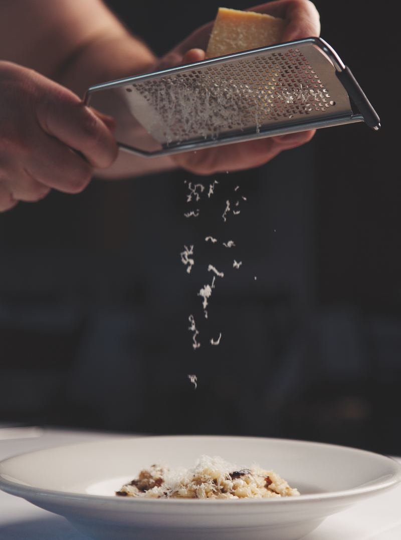 Parmesan being grated over a plate of risotto