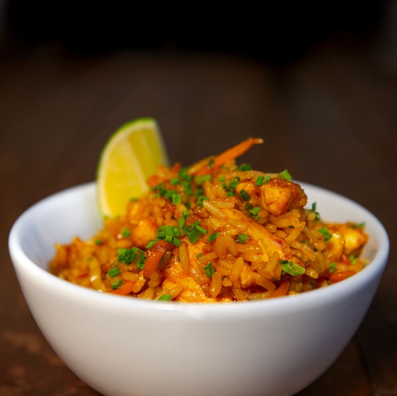 Bowl of spiced rice with chives and a wedge of lime