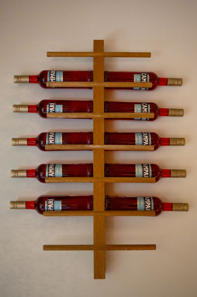Wooden wall rack holding bottles of Campari